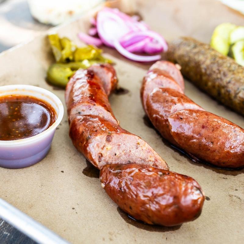 A BBQ plate with sausage, meat, and sides